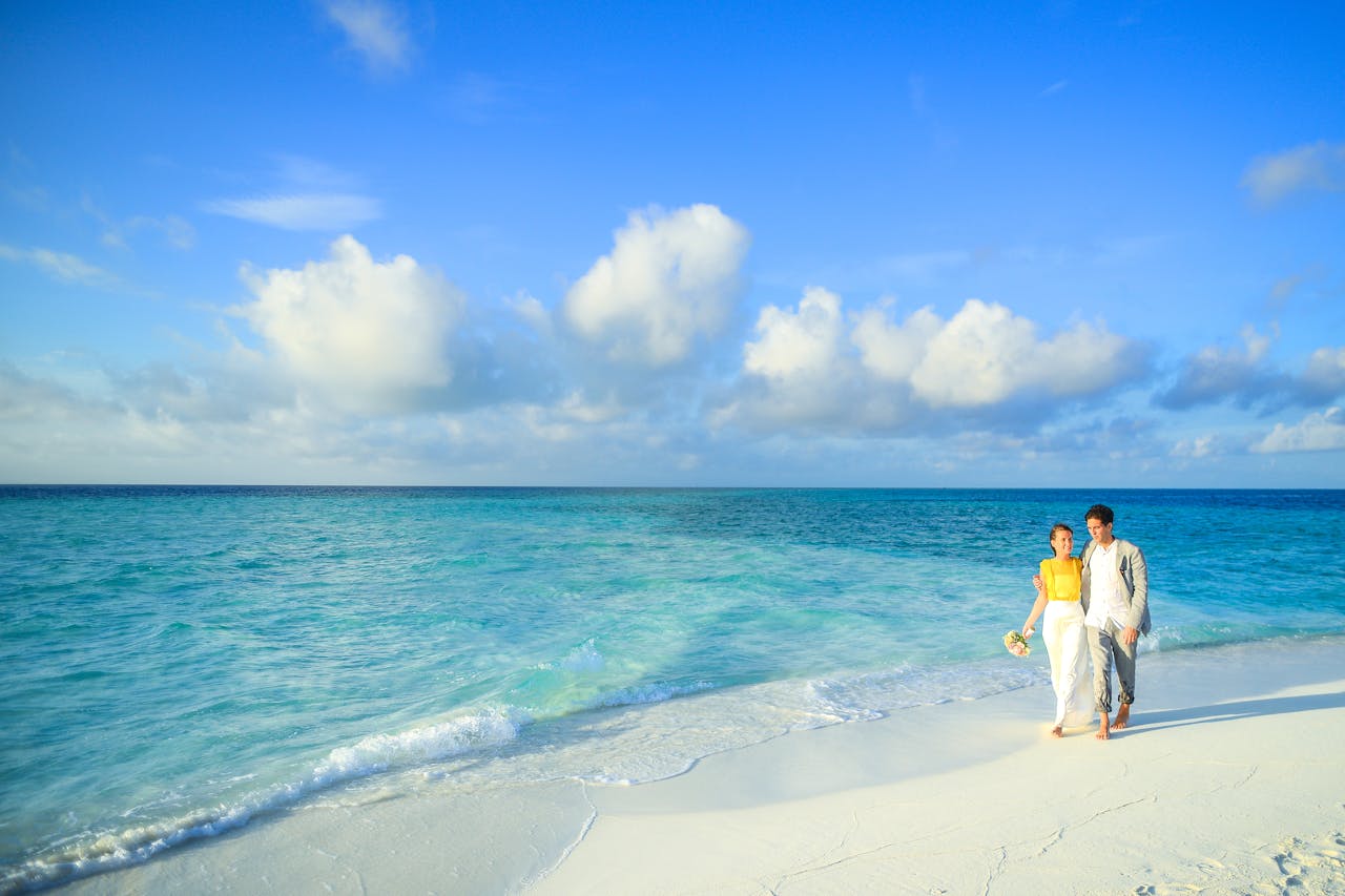 services-02 A couple enjoys a romantic stroll along a pristine tropical beach with turquoise waters.
