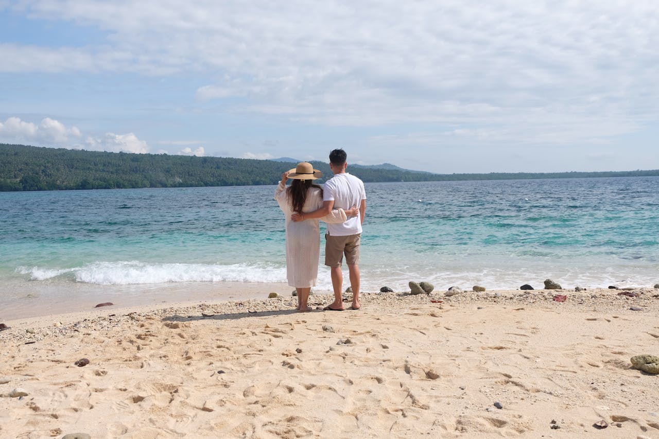 about-01 A couple embracing on a beautiful Philippine beach overlooking a tranquil sea.